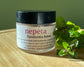 Nepeta Tendonitis Salve jar with nepeta plant on a wooden surface